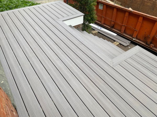Gray composite deck with linear board pattern, built-in bench seating, and integrated planter boxes overlooking landscaped yard.